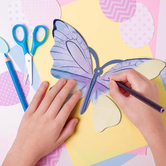 Children's hands working on a craft project with scissors, markers, and a butterfly template on a colorful background.