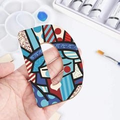 Colorful abstract patterned phone case held by a hand with art supplies in the background