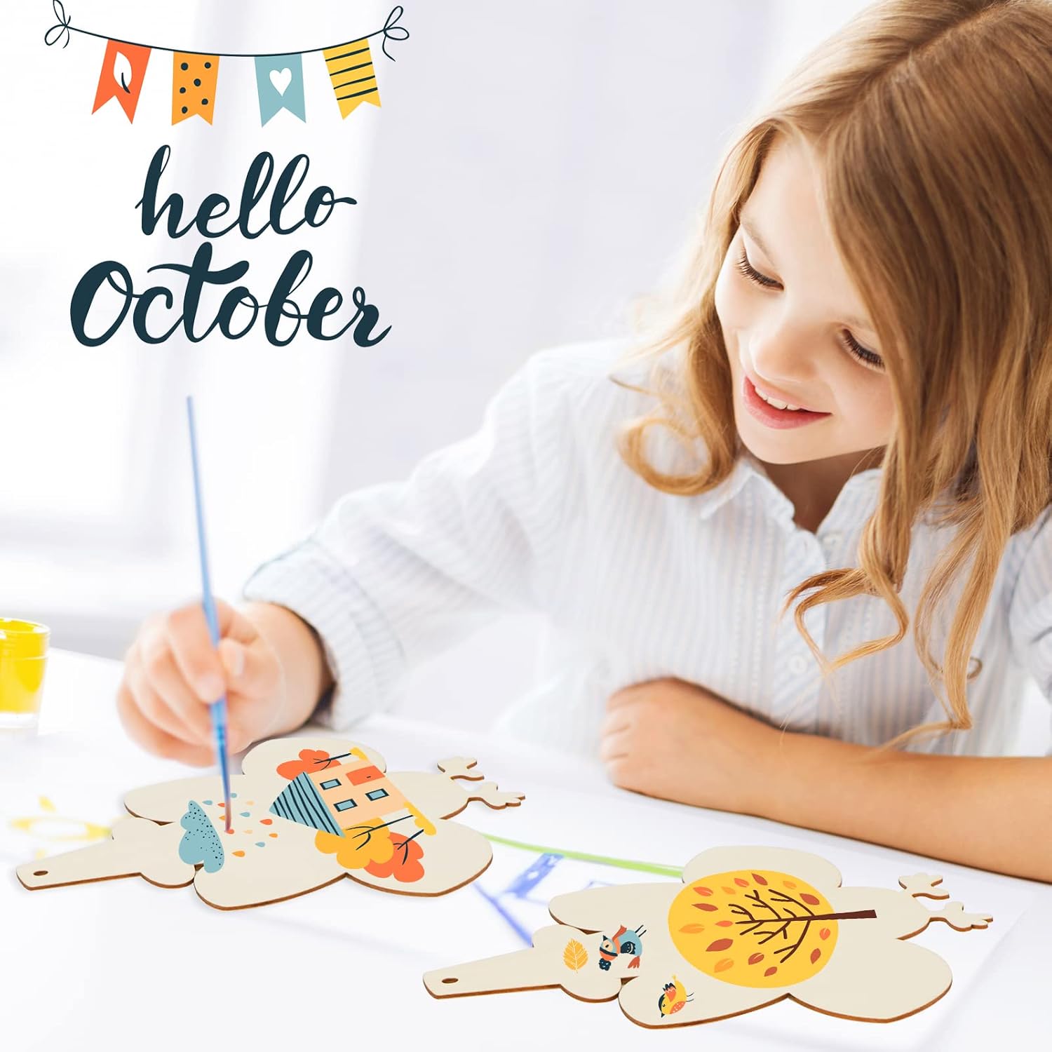 Child painting wooden crafts with 'hello October' text and colorful flags in the background