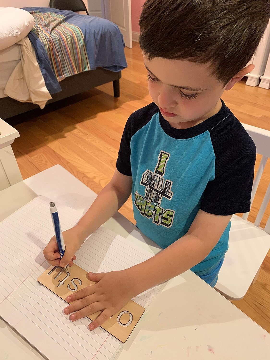 Child writing on a wooden board with a pen in a home setting