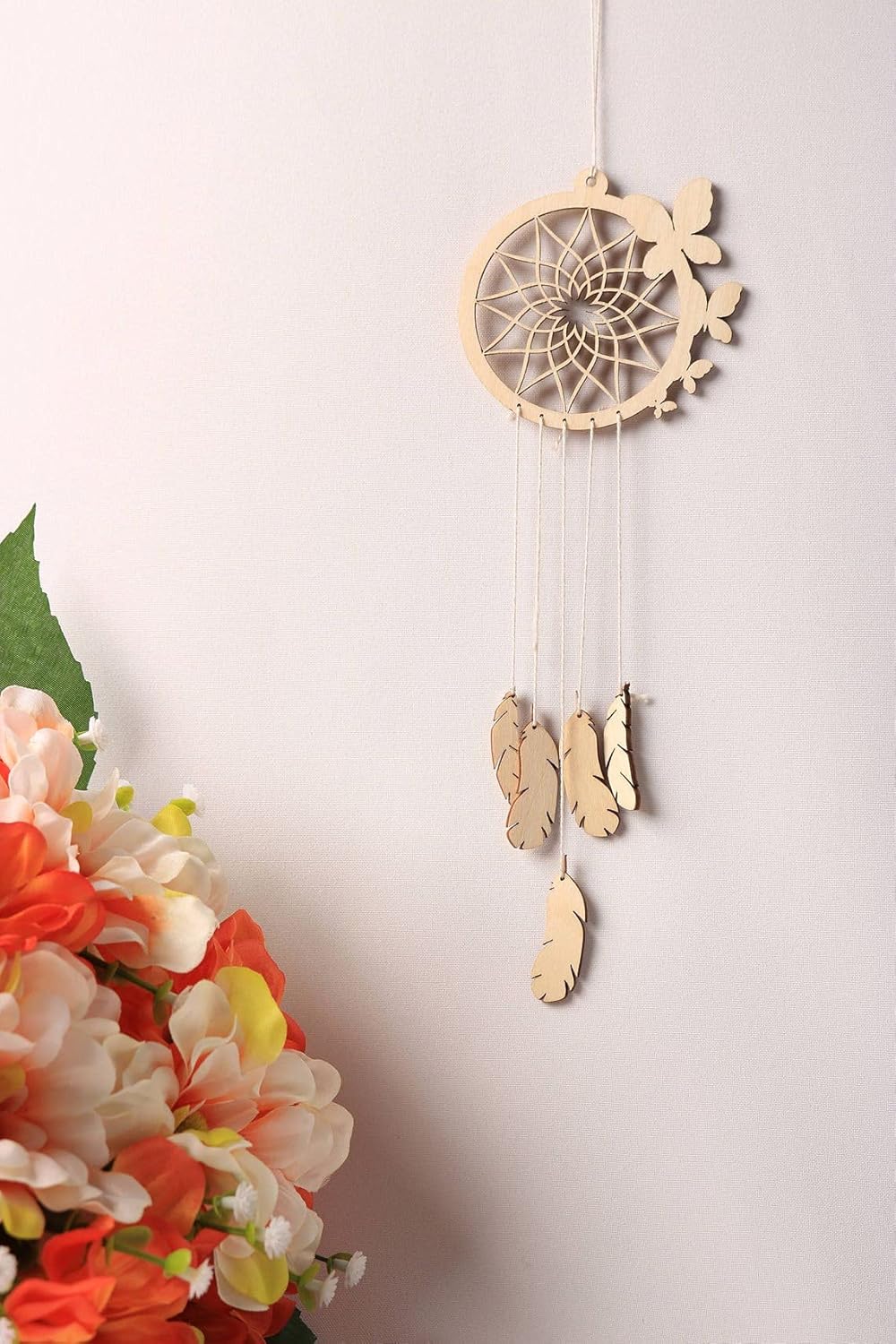 Wooden dreamcatcher with feathers and flowers on a white background