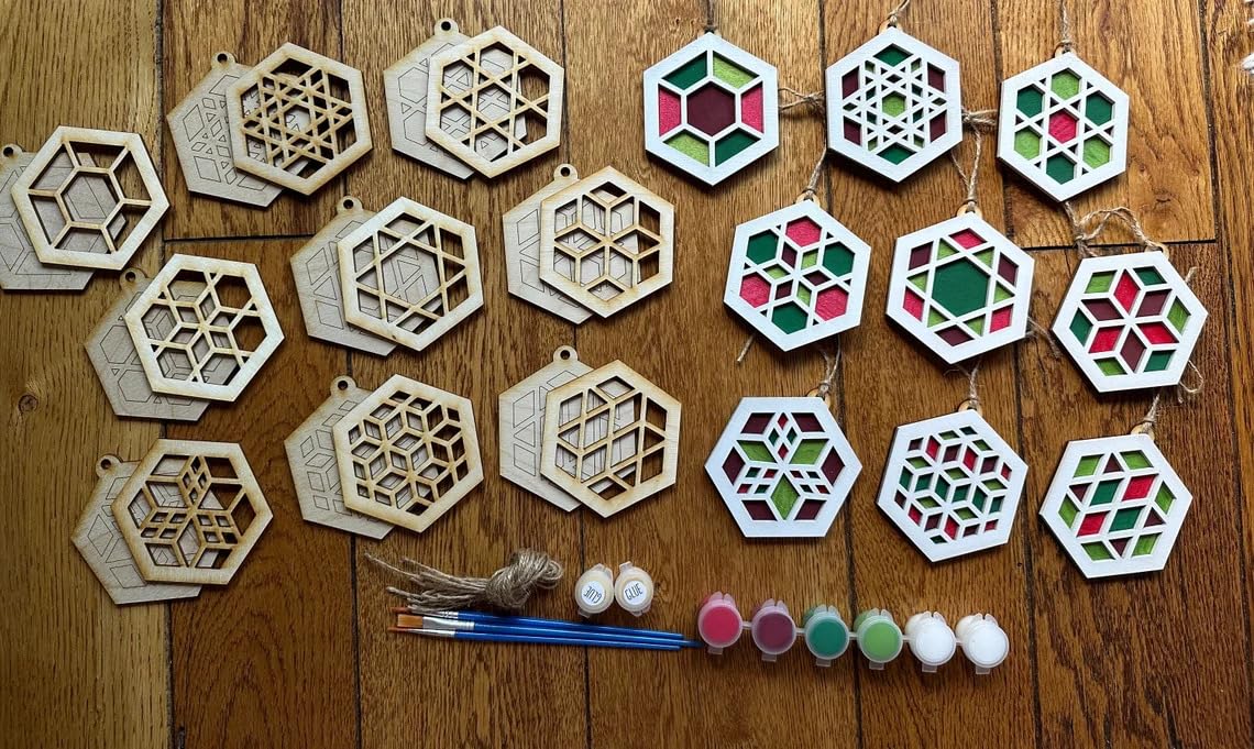 Hexagonal wooden ornaments with paint and brushes on a wooden surface