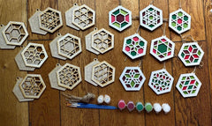 Hexagonal wooden ornaments with paint and brushes on a wooden surface