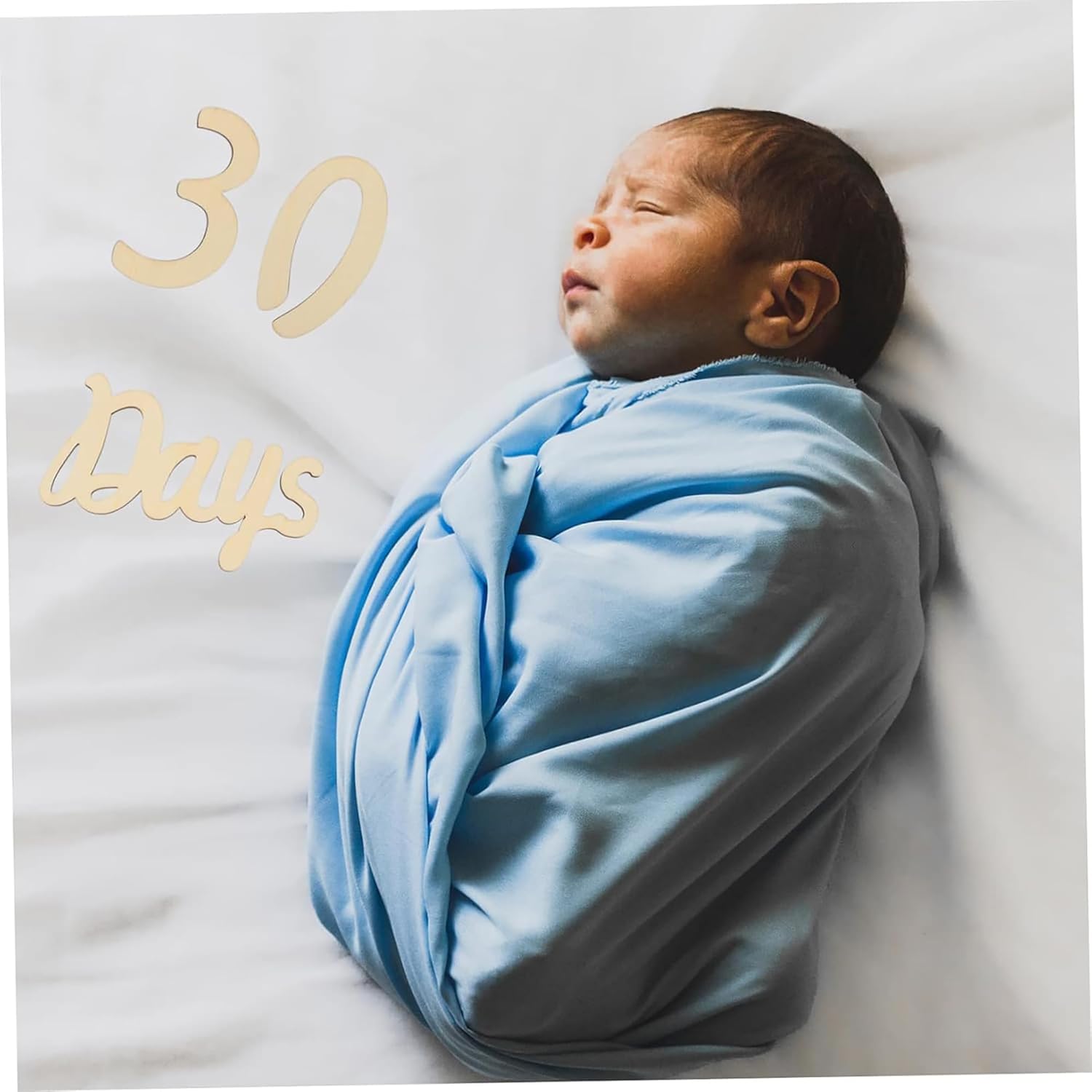 Newborn baby wrapped in a blue blanket with '30 Days' text on a white background