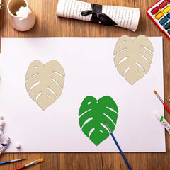 Artistic depiction of tropical leaves on a white sheet with painting tools around.