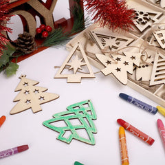 Wooden Christmas tree ornaments on a white surface with crayons and festive decorations.
