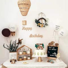 Birthday party setup with cake, decorations, and 'Happy Birthday' signs on a white wall.