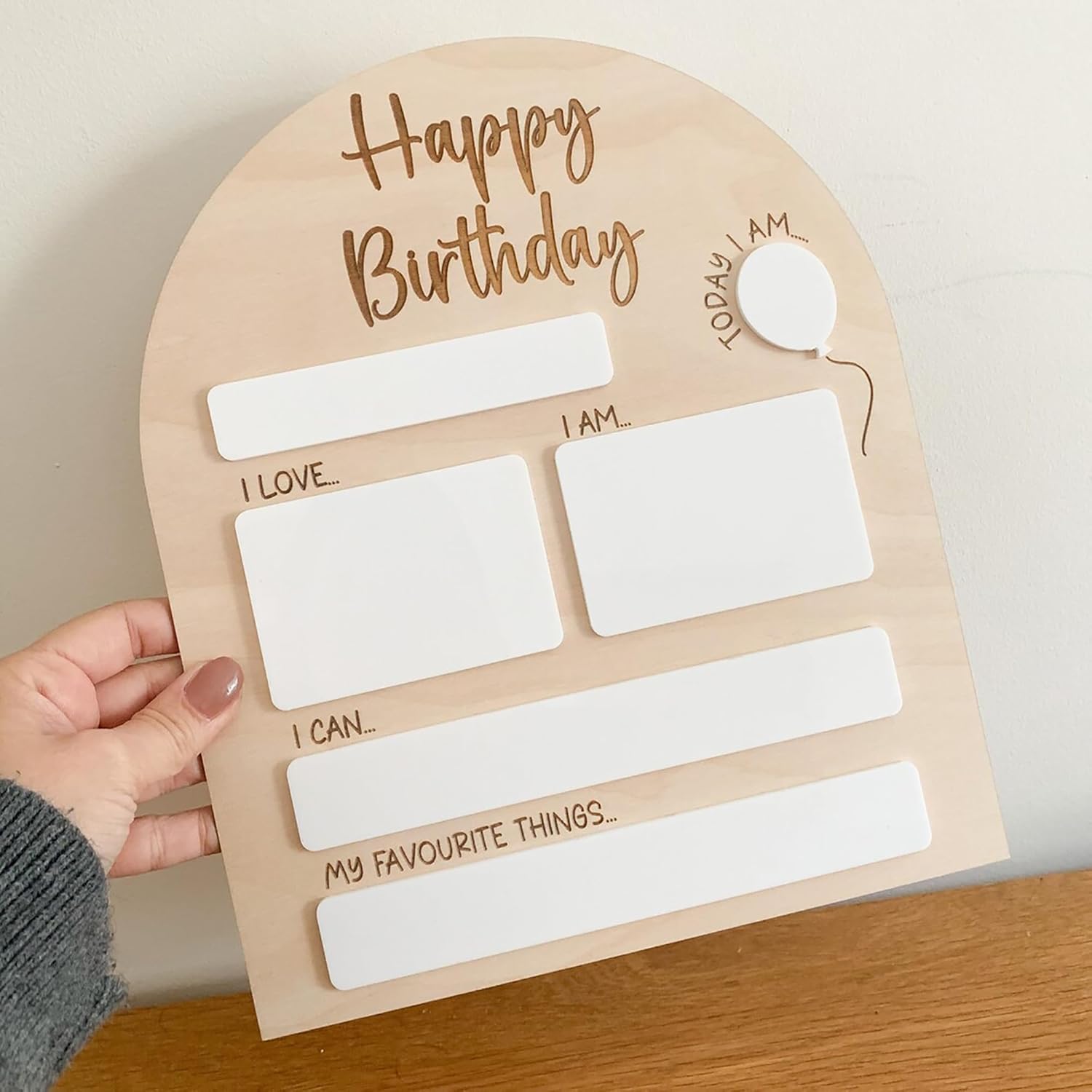 Wooden birthday questionnaire board held by a hand on a wooden surface.