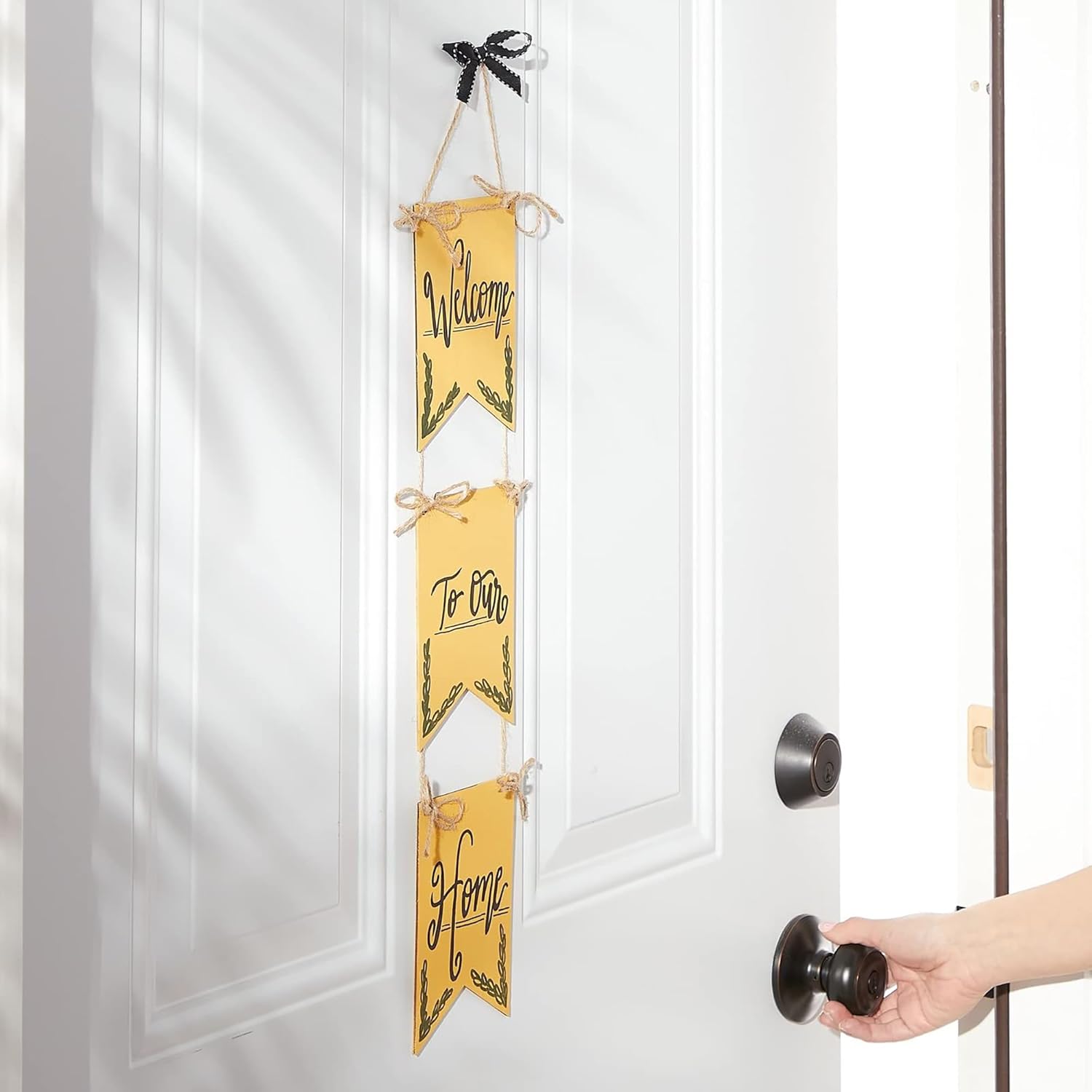 Decorative sign with 'Welcome To Our Home' text hanging on a white door.