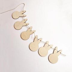 Wooden bunny shapes on a string against a light pink background