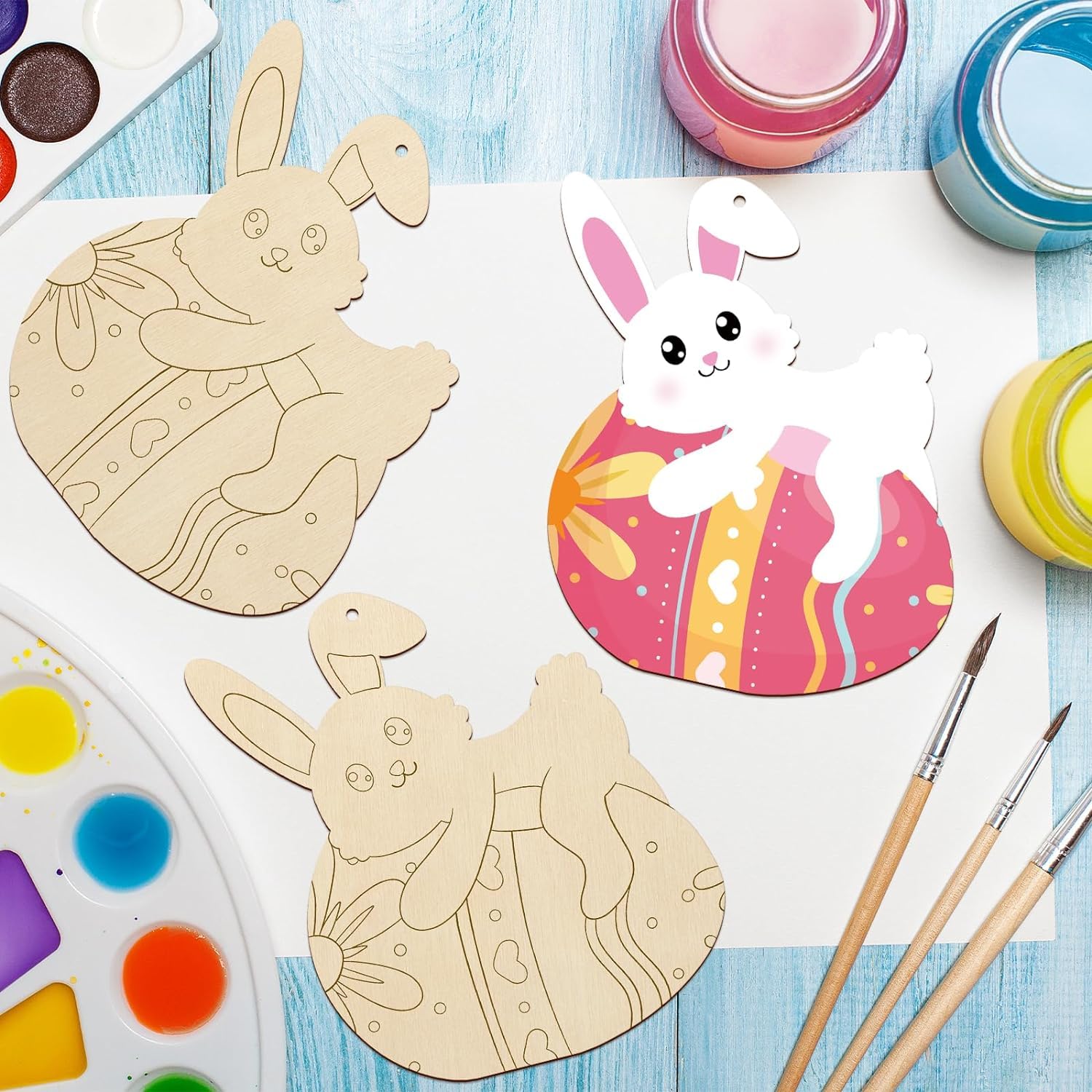 Wooden bunny shapes with paint and brushes on a blue surface