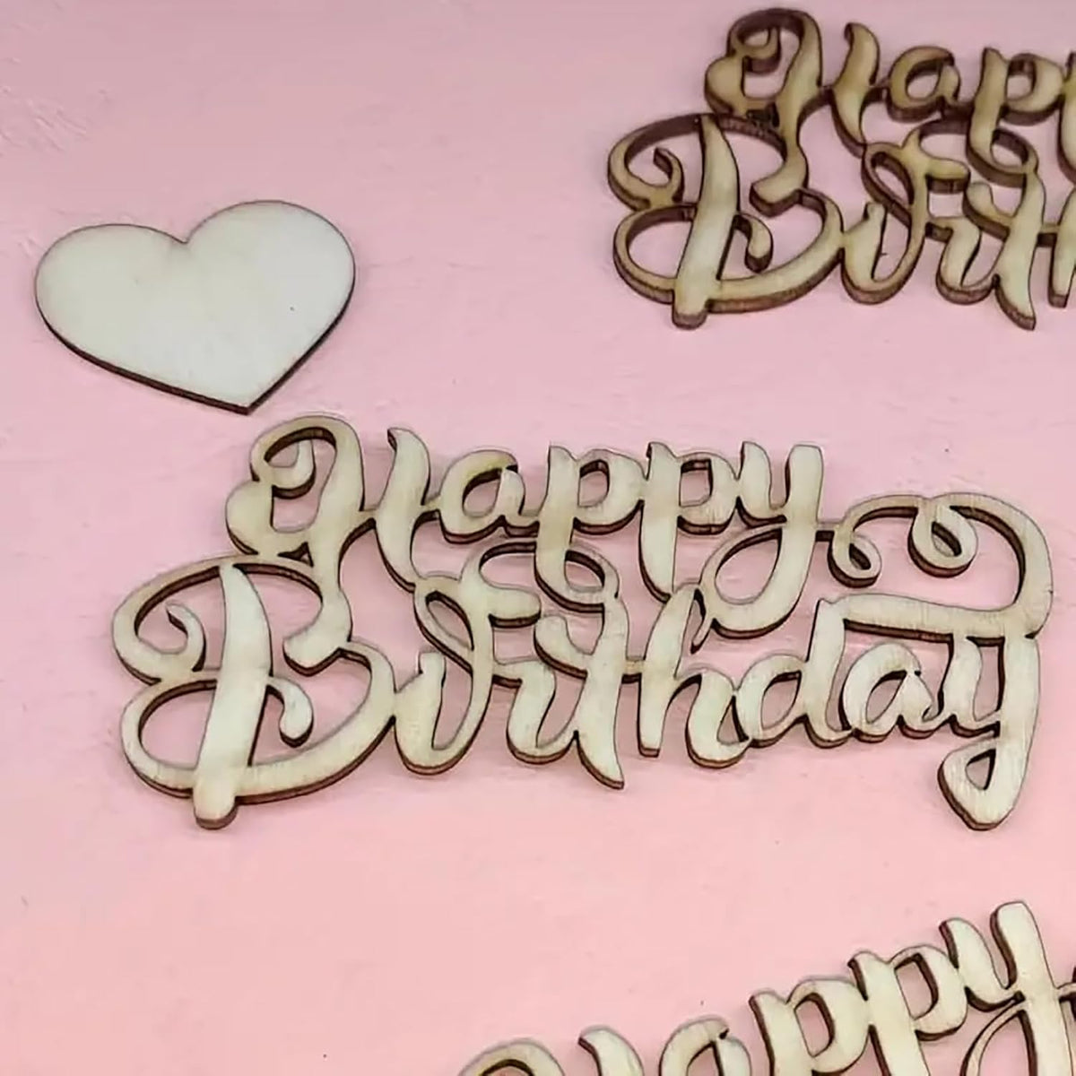 Wooden 'Happy Birthday' and heart decorations on a pink background