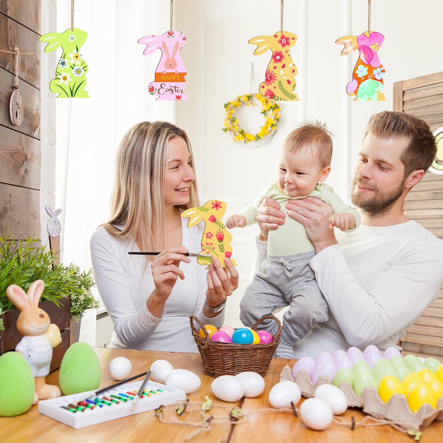 Family with a baby engaging in Easter egg decorating activities.