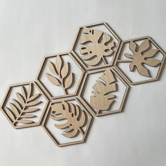Hexagonal wooden coasters with leaf patterns on a light gray background