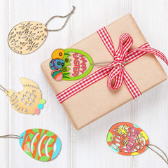 Gift wrapped in brown paper with a red checkered ribbon, surrounded by colorful Easter-themed cutouts on a light wooden surface.