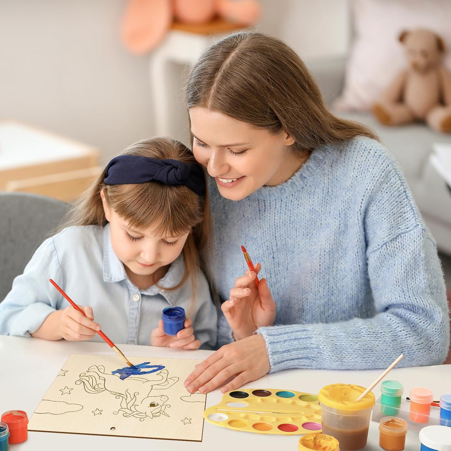 Woman and child painting together with art supplies on a table.
