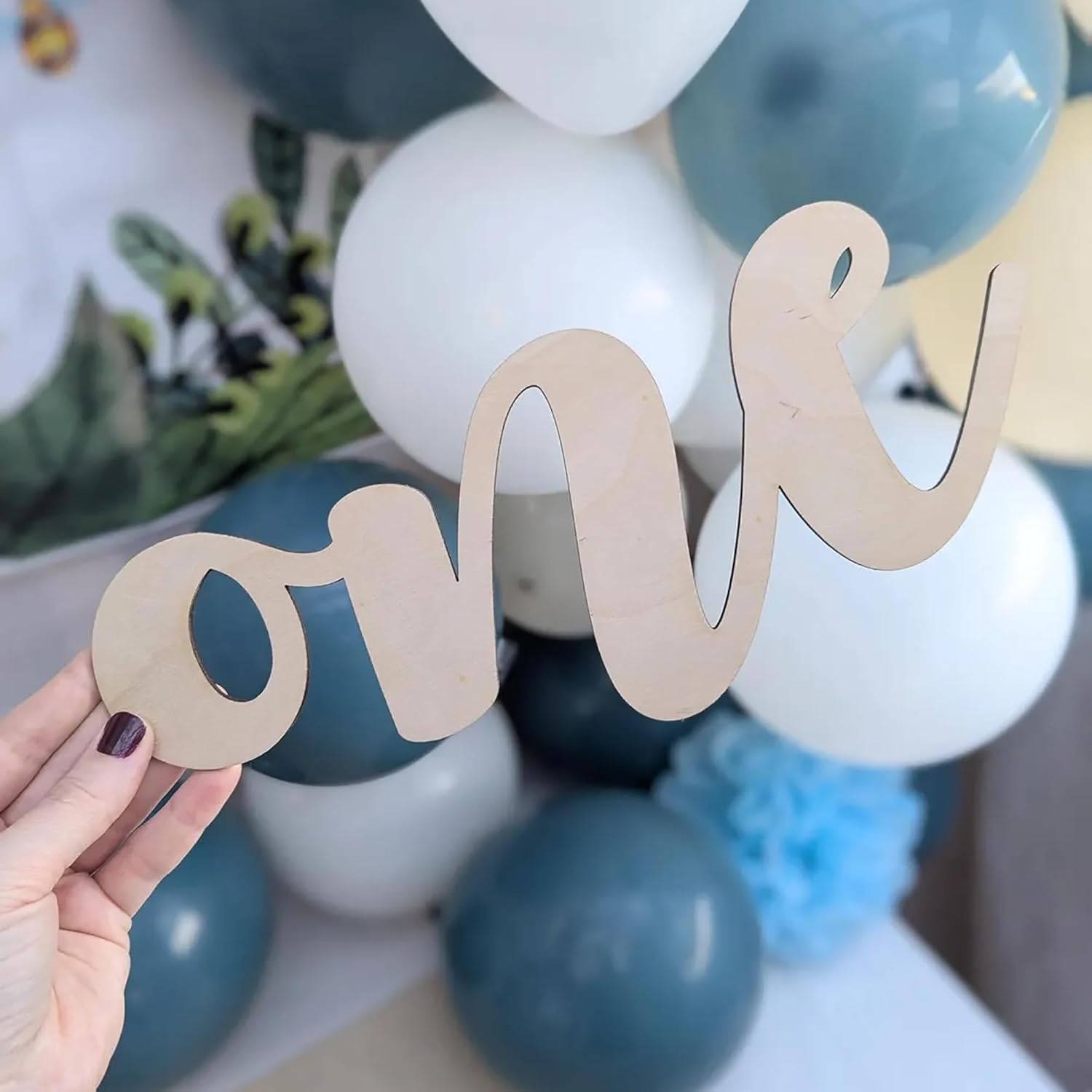 Wooden 'one' decoration held over balloons in blue and white.