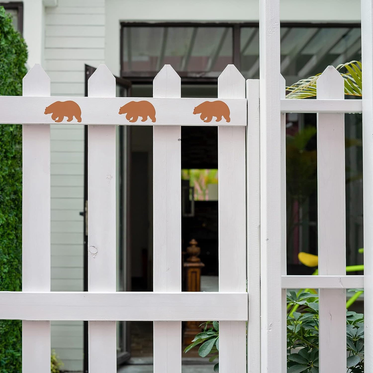 White picket fence with bear stickers in front of a house.