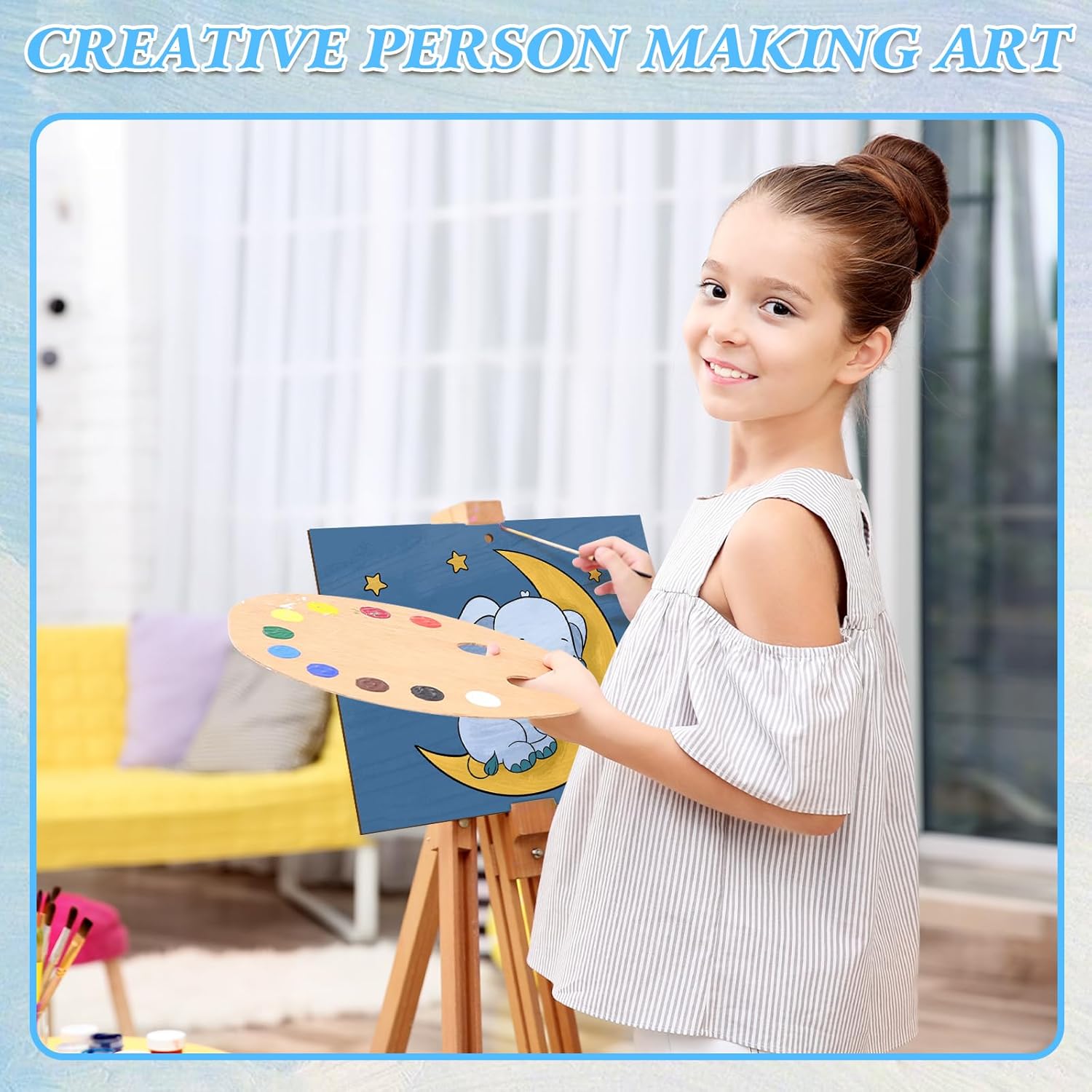 Young girl painting with a smile, holding a palette and a canvas with a blue background.