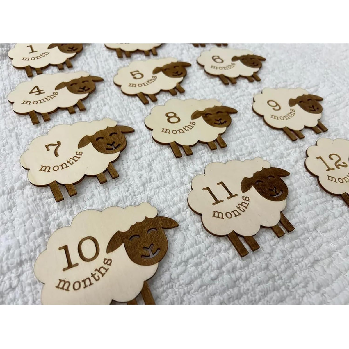 Wooden sheep-shaped milestone cards with numbers on a white background