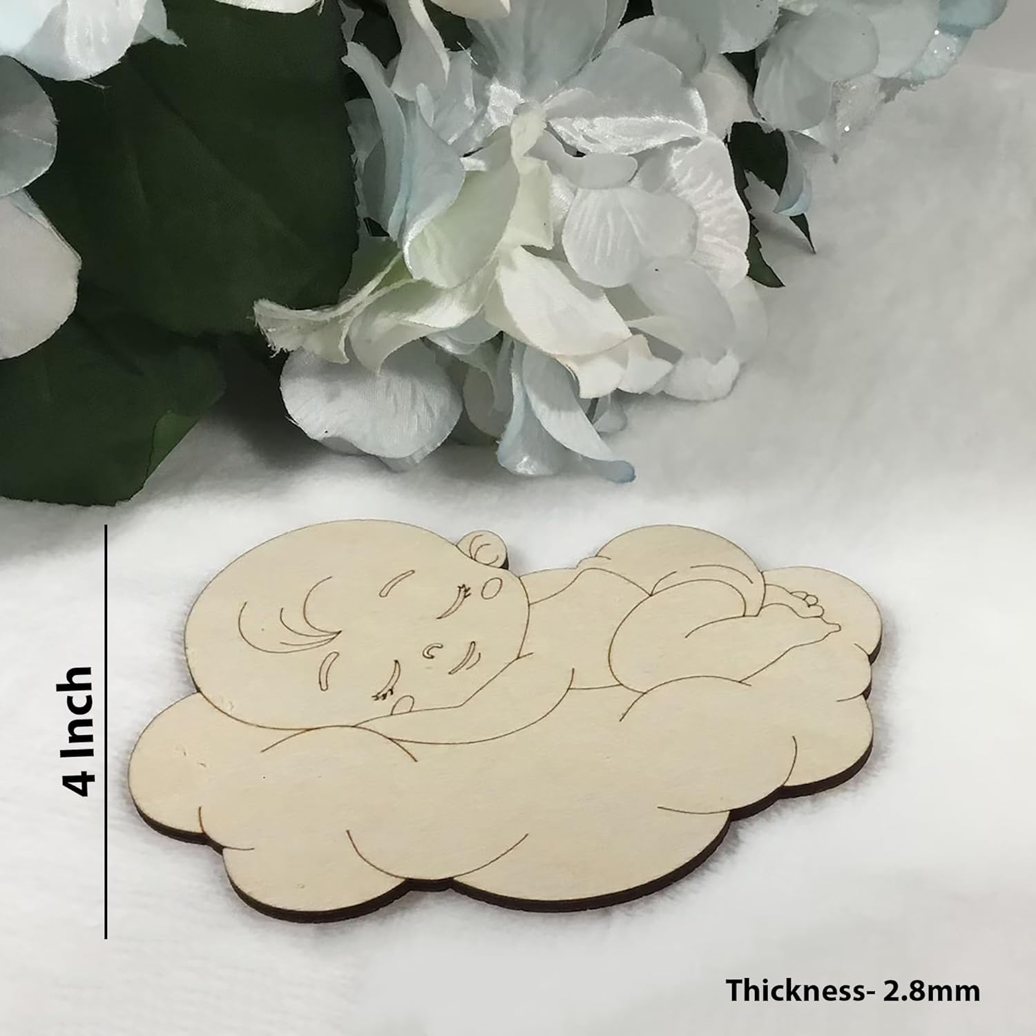 Wooden cutout of a baby on a cloud with measurements and thickness details, placed on a white surface with flowers in the background.