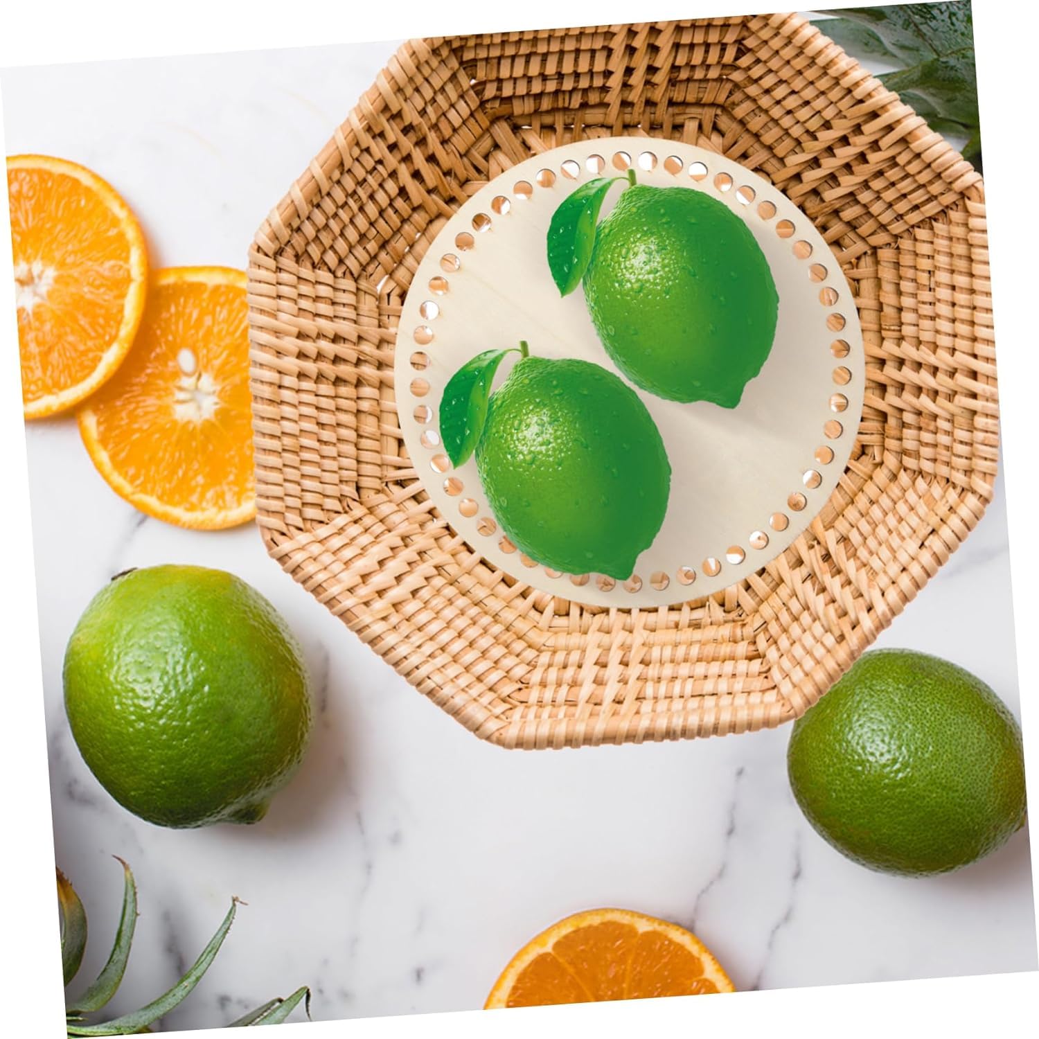 Green limes on a woven plate with orange slices on a marble background