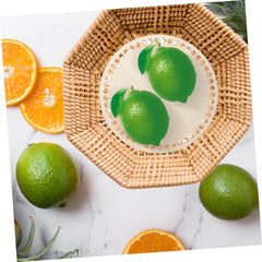 Green limes on a woven plate with orange slices on a marble background