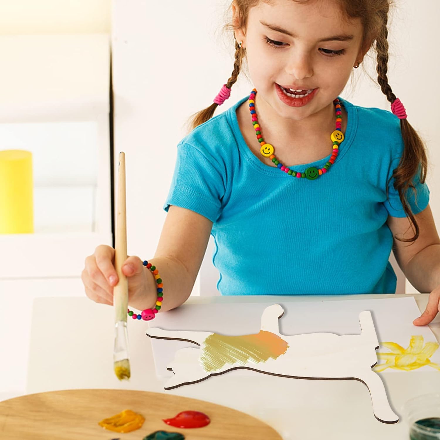 Child painting a picture of a fish with a brush and colorful paint.