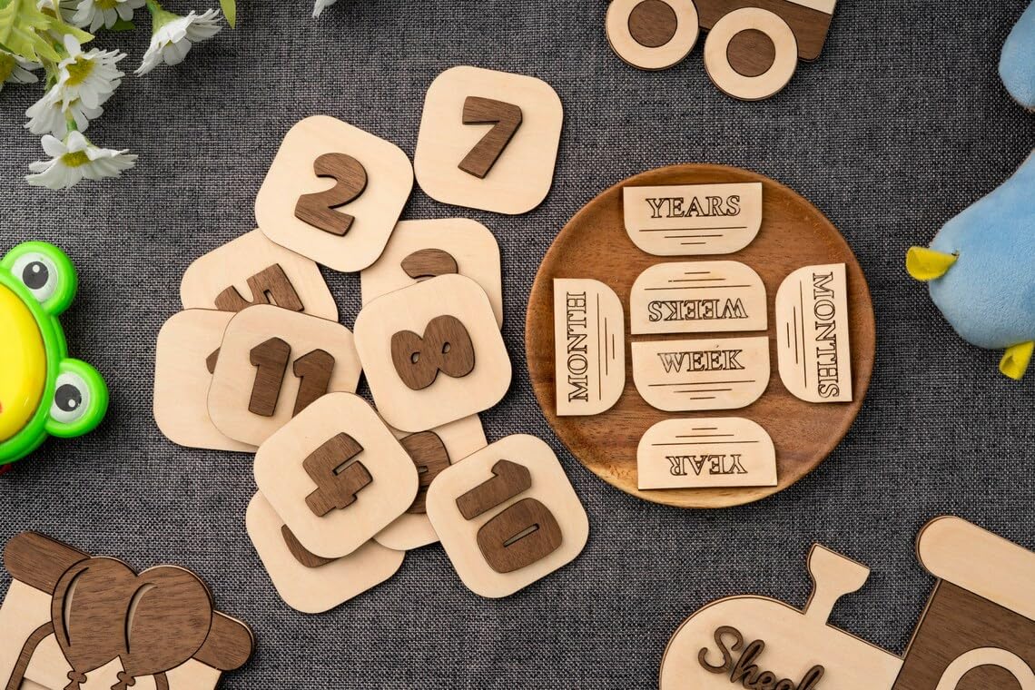 Wooden numbers and milestone cards on a textured surface with toys around