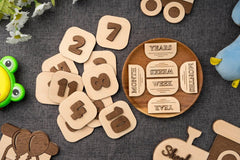 Wooden numbers and milestone cards on a textured surface with toys around