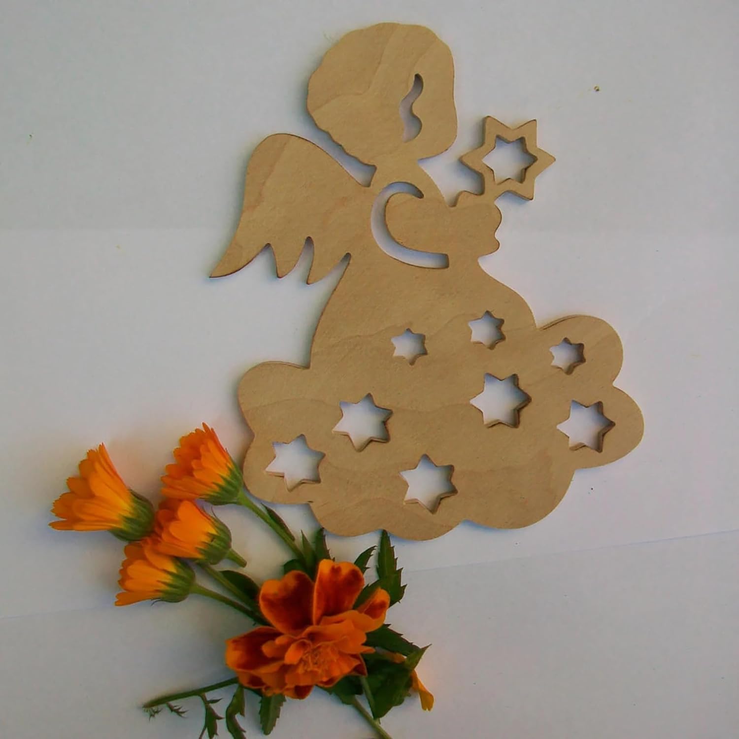 Wooden angel cutout with star shapes and orange flowers on a white background