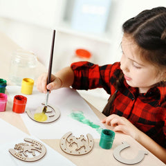 Child painting wooden ornaments with colorful paint and brushes on a table.