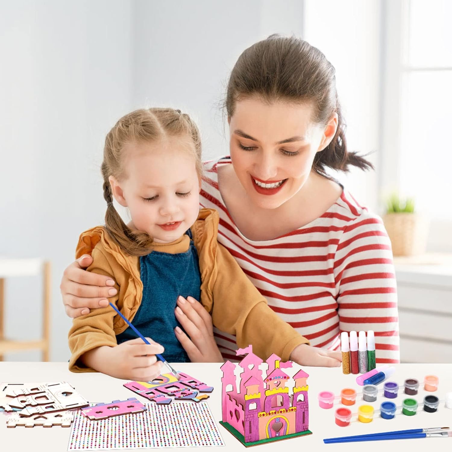 Woman and child painting a pink castle model together.