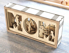 Wooden decorative box with cut-out figures on a wooden surface