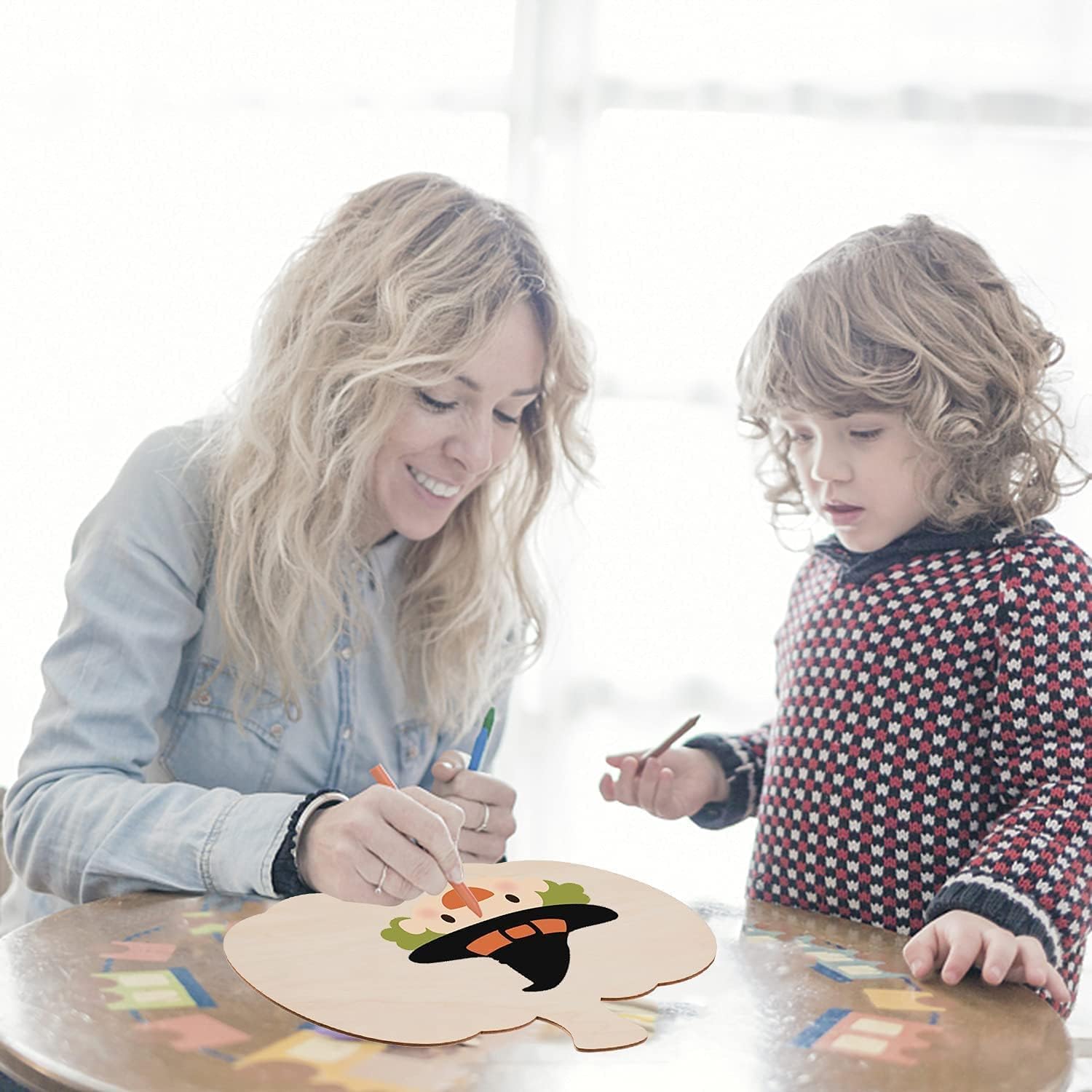 Woman and child painting a wooden board together on a light background