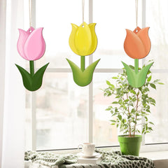 Three colorful tulip-shaped planters hanging by a window with a plant and cup on a windowsill.