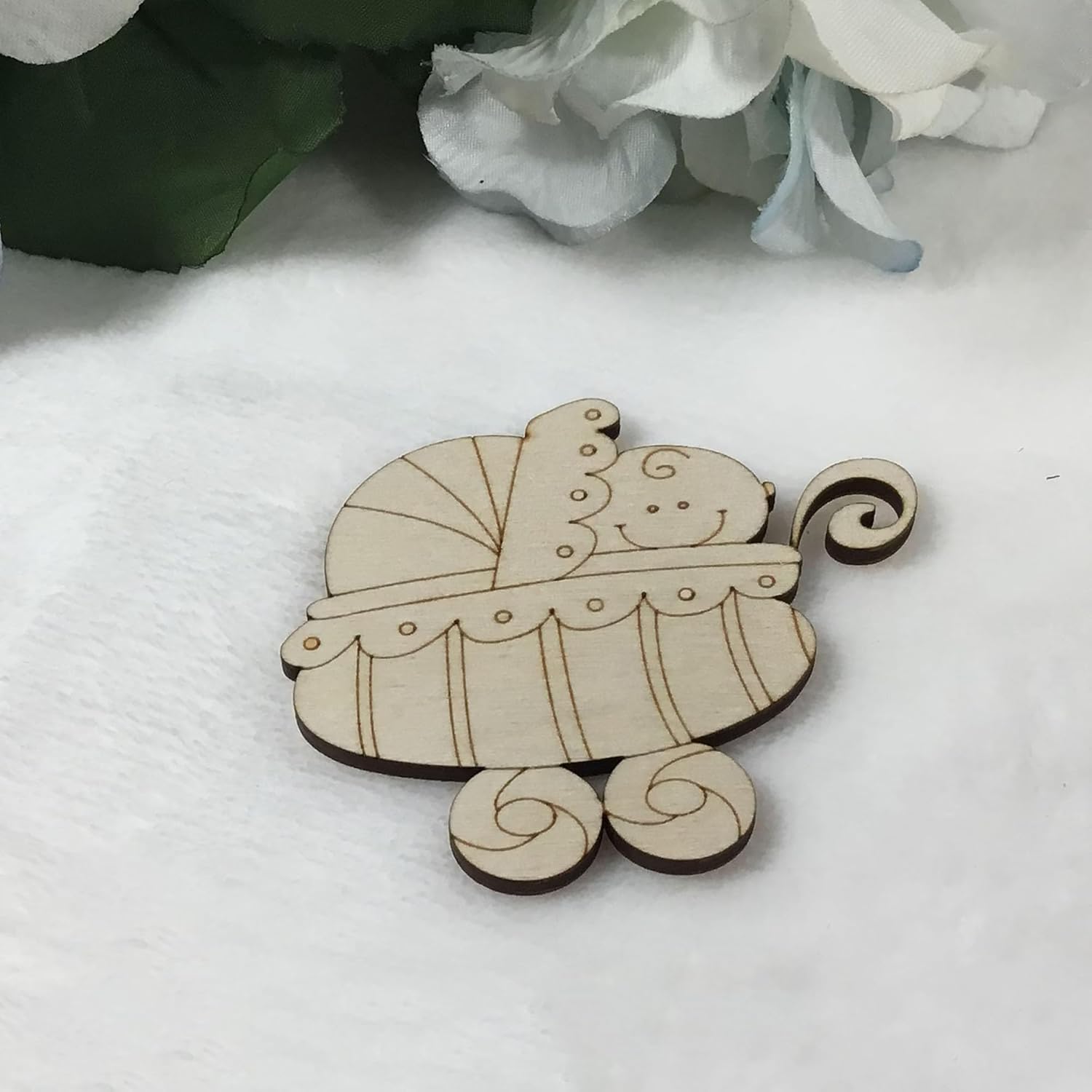 Wooden toy carriage on a white surface with flowers in the background