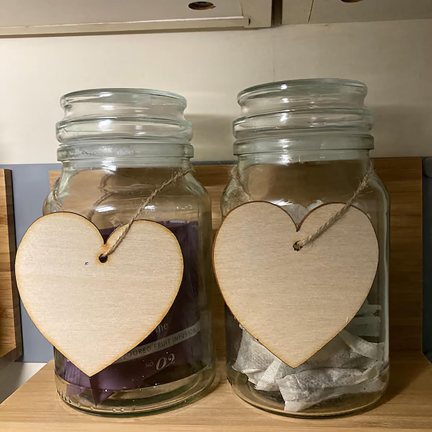 Two glass jars with wooden heart-shaped tags on a wooden surface.