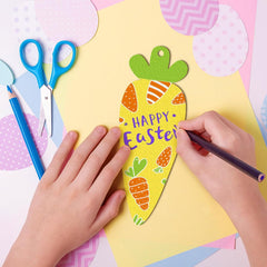 Child's hands decorating a yellow Easter card with colorful cutouts on a pink background.