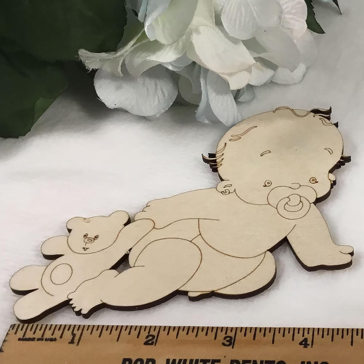 Wooden baby toy with a pacifier and teddy bear, next to a ruler for scale.