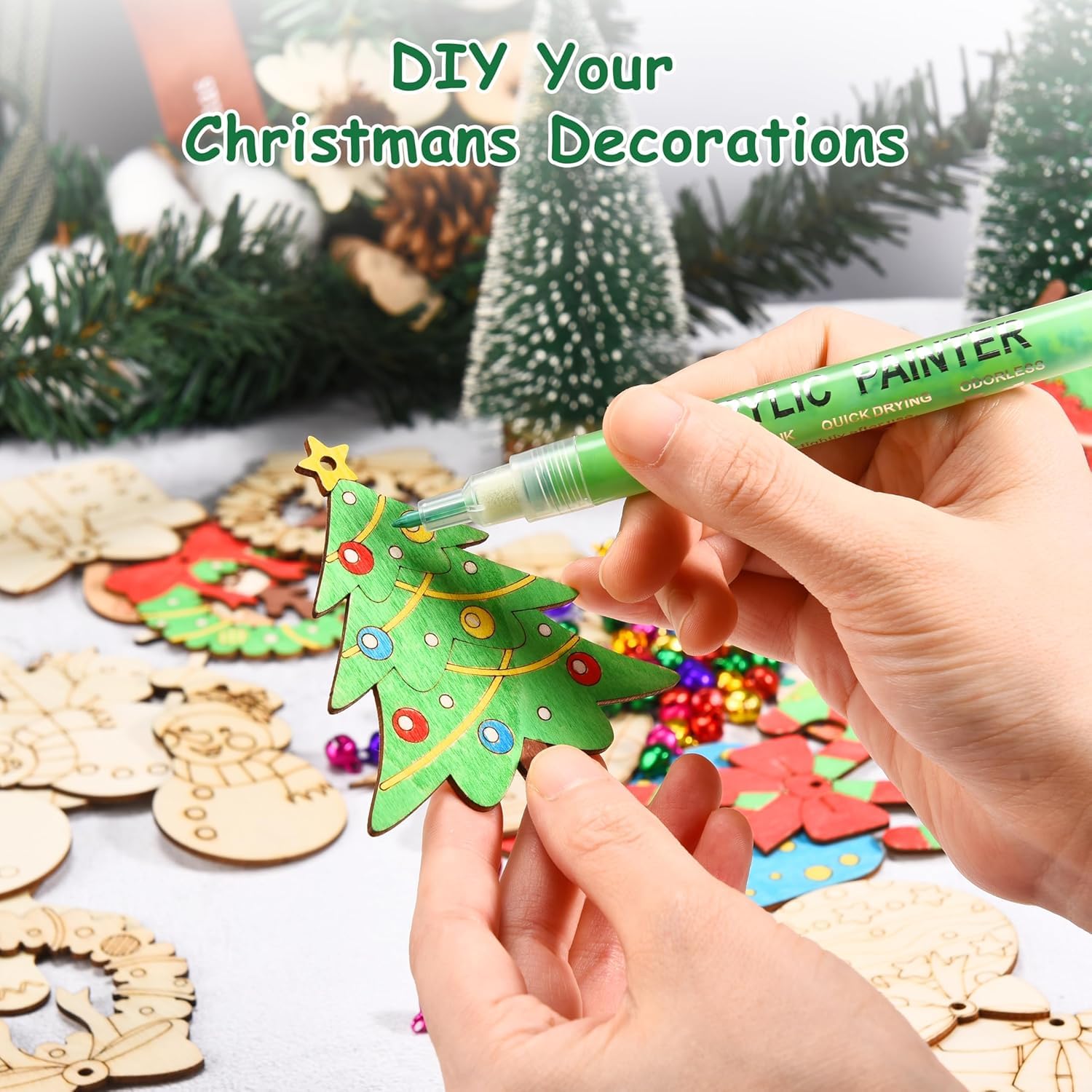 Person decorating a Christmas tree-shaped wooden cutout with colorful markers, surrounded by other decorative items.