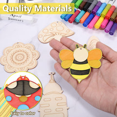 Hand holding a colorful wooden bee ornament with other wooden cutouts and markers on a white background.