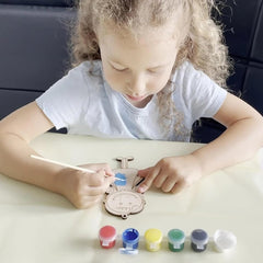 Child painting a decorative item with colorful paint containers on a table.