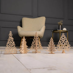 Set of decorative wooden Christmas trees on a marble surface with a chair and table in the background.
