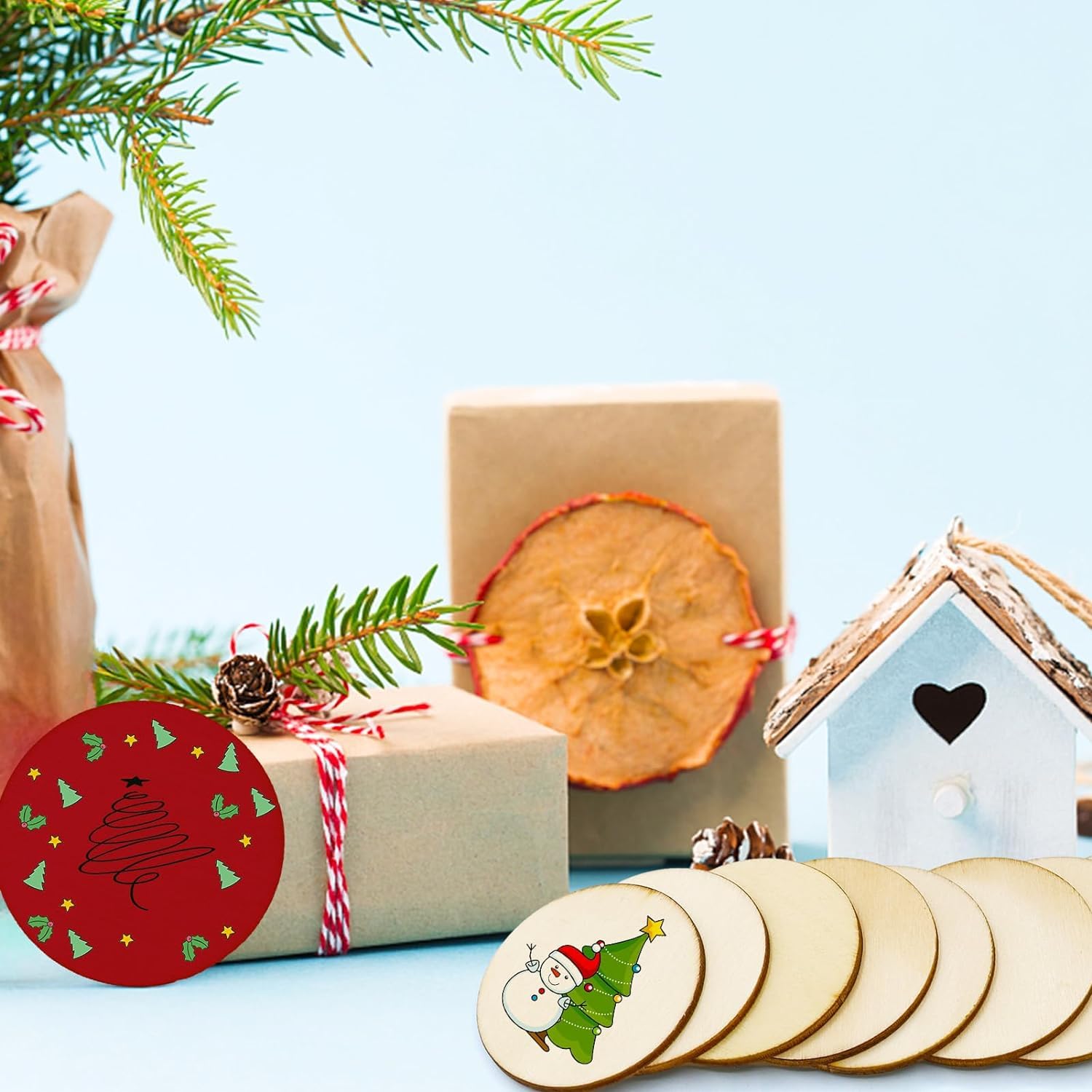 Christmas-themed items including wrapped gifts, a red ornament, and wooden coasters on a light blue background.