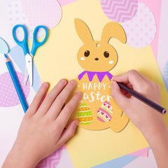 Child's hands coloring a paper Easter bunny with 'Happy Easter' text on a colorful background.