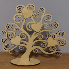 Wooden tree-shaped decorative item with heart designs on a wooden surface.