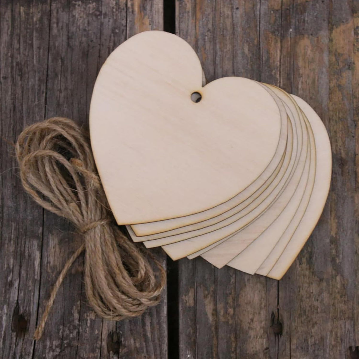 Stack of wooden heart-shaped tags with twine on a rustic wooden background