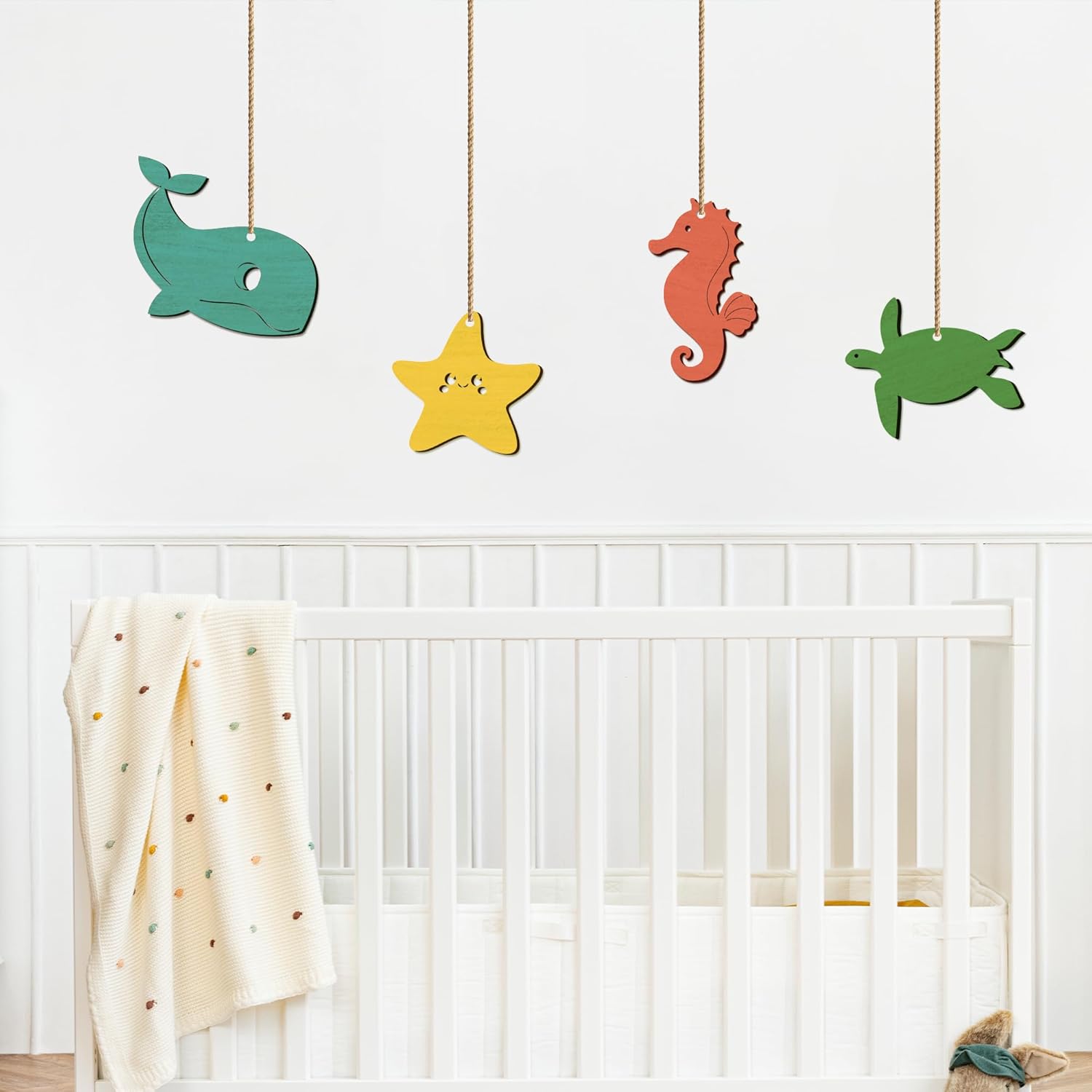 Colorful wooden sea creature toys hanging above a crib in a nursery.