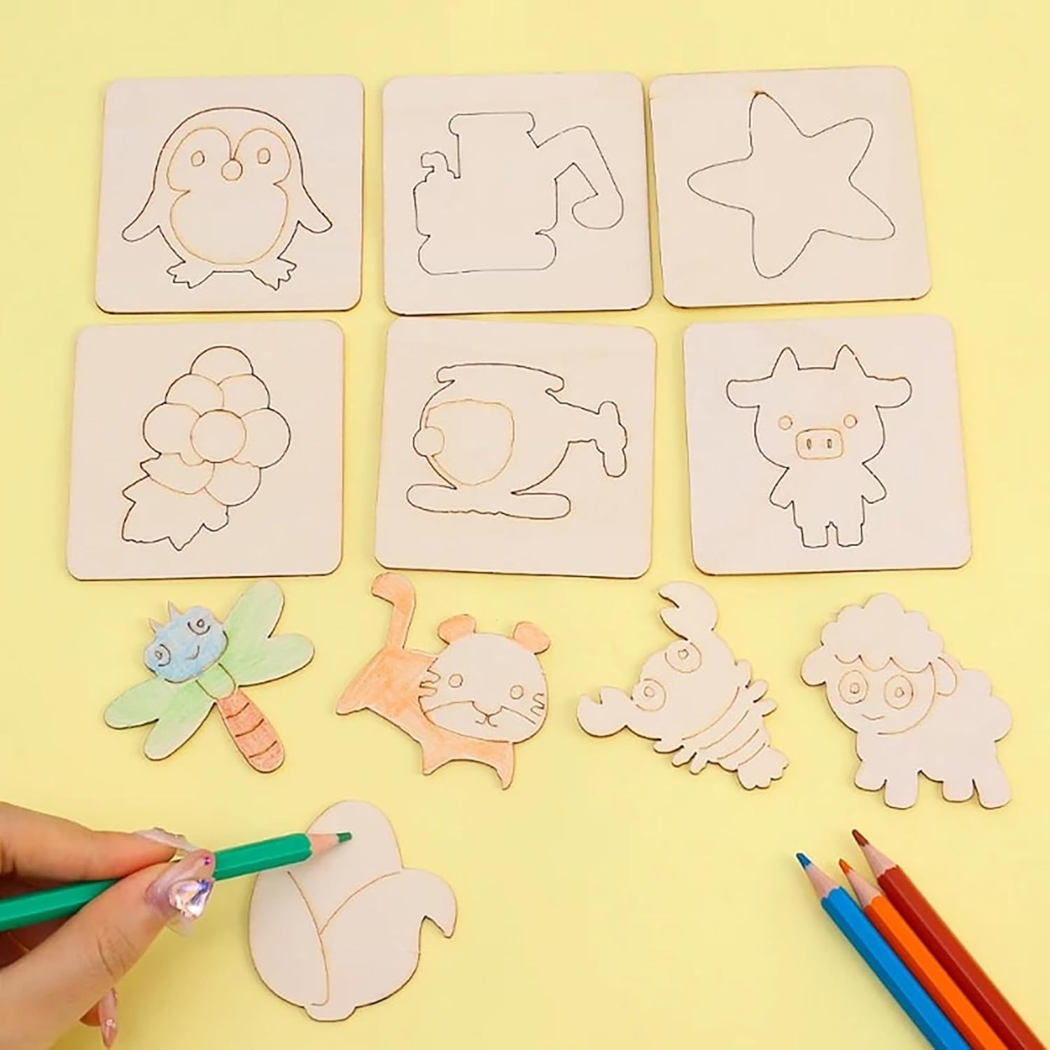 Wooden stamps with animal shapes on a yellow background, with a hand holding a stamp and colored pencils.